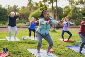 Fit multiracial senior people doing yoga exercise at city park - Mental health concept